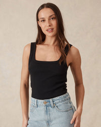 Thumbnail for Woman wearing a black tank top and light blue jeans against a beige background