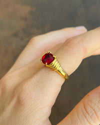 Thumbnail for Gold ring with a red gemstone on a neutral background