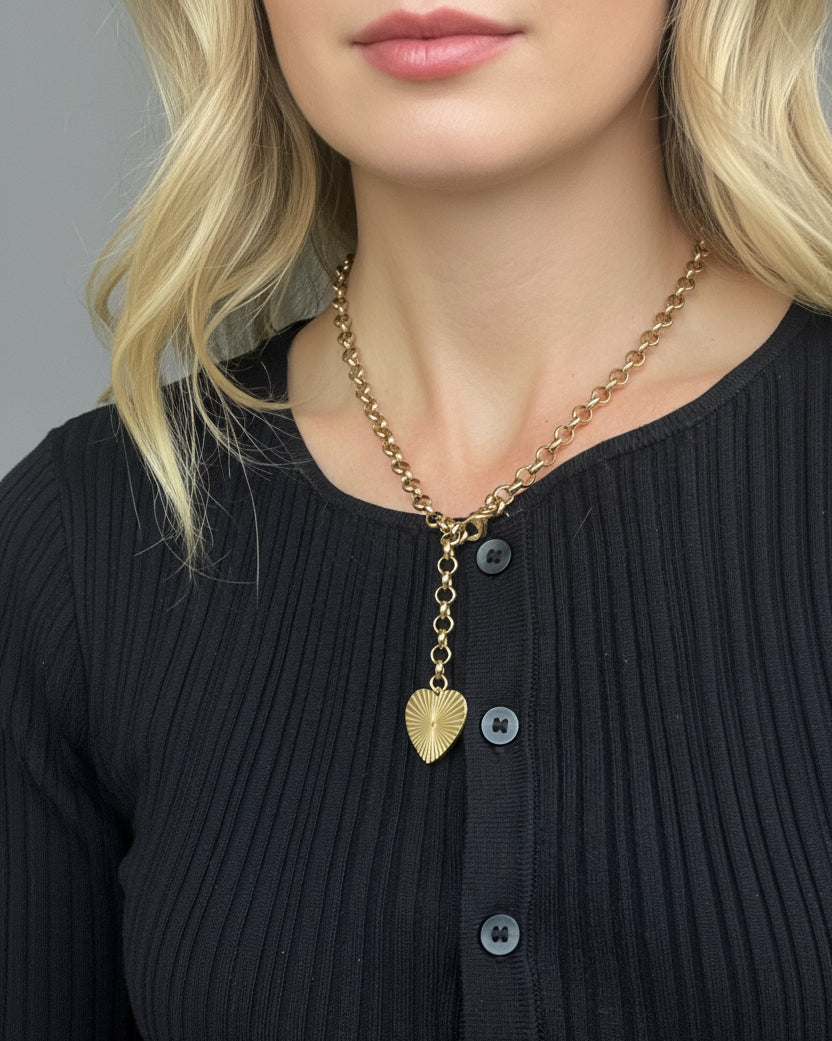 Gold necklace with a heart pendant on a black ribbed sweater.