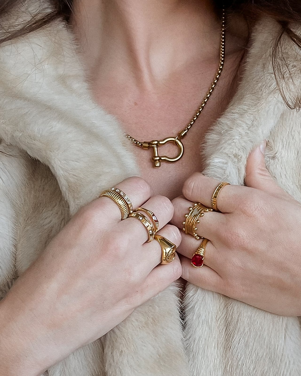 Close-up of hands wearing gold rings with a fur coat background
