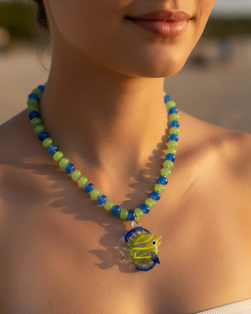 Close-up of a person wearing a colorful beaded necklace with a fish pendant on a blurred background