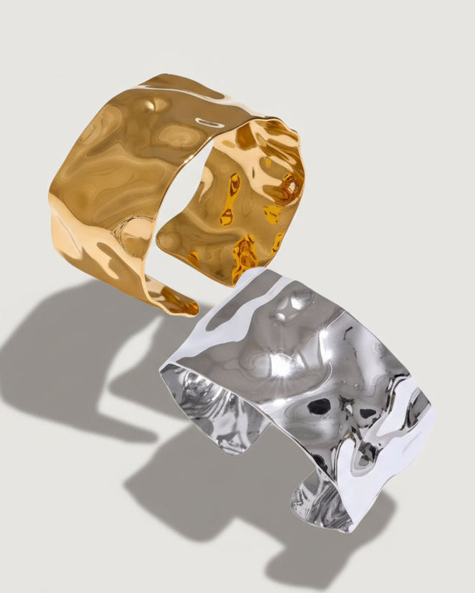 Gold and silver cuff bracelets on a light gray background