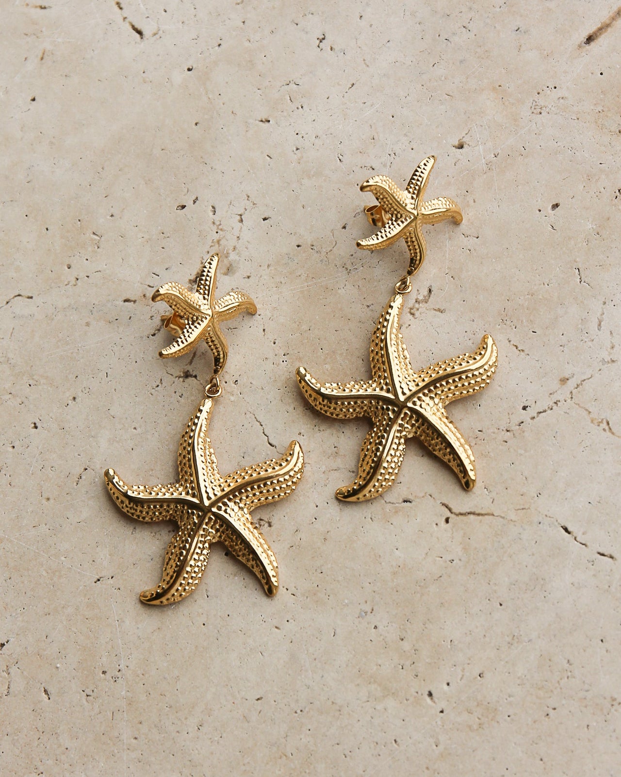 Gold starfish drop earrings by Tegan Rae Jewellery featuring delicate starfish charms hanging from elegant earring hooks.