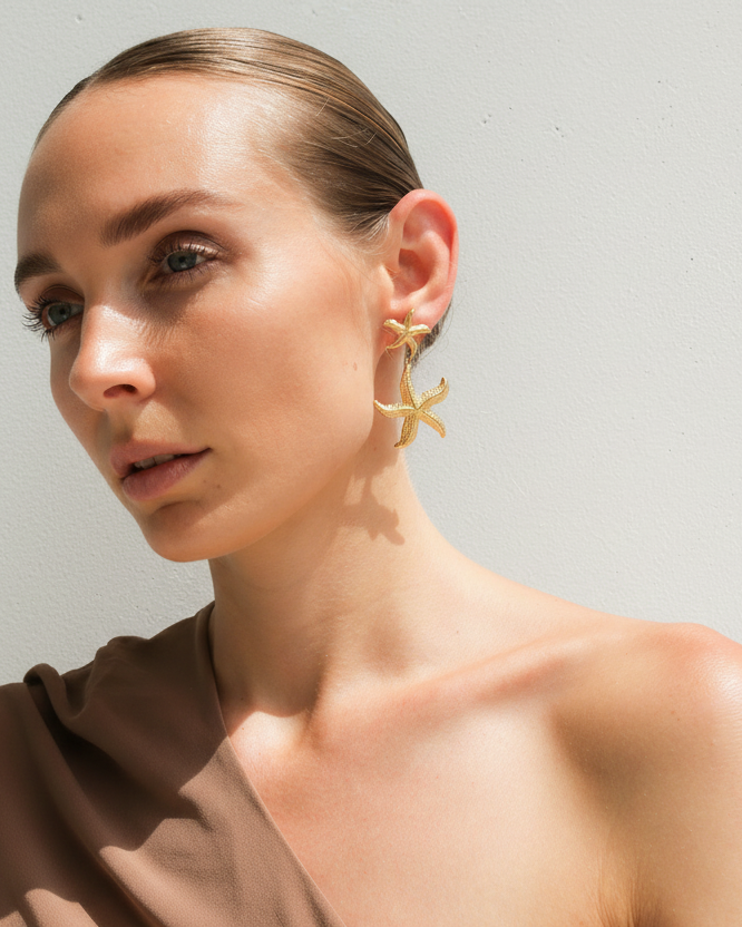 Gold starfish drop earrings by Tegan Rae Jewellery featuring delicate starfish charms hanging from gold hooks.