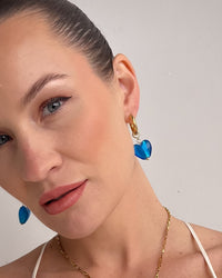 Thumbnail for nikki wearing gold necklace and blue heart earrings against a plain background