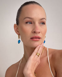 Thumbnail for nikki wearing gold jewelry with blue earrings against a plain background