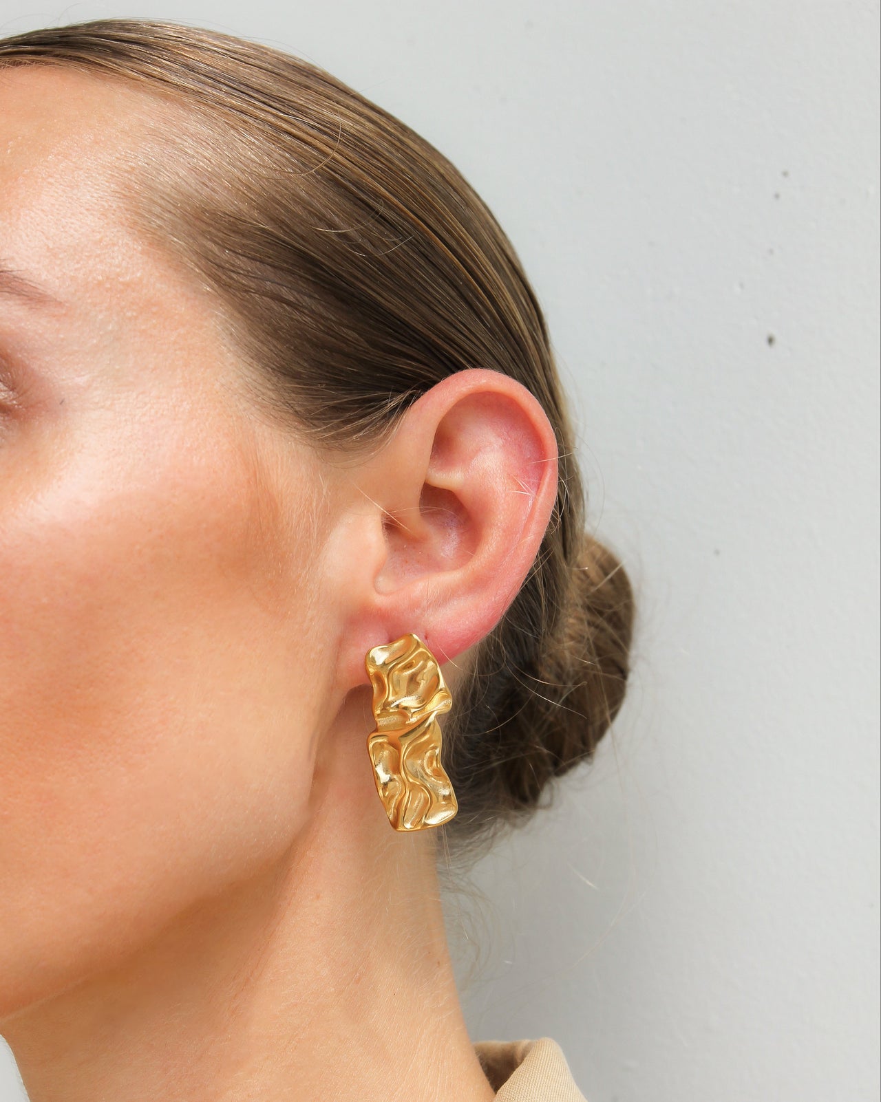 Gold textured stud earrings by Tegan Rae Jewellery, close-up of small, round, hammered surface earring design.