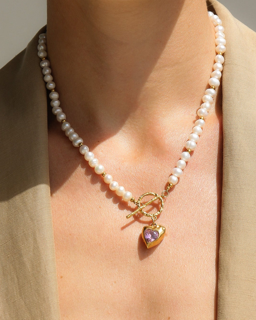 Gold heart-shaped freshwater pearl necklace with pink stone accents from Tegan Rae Jewellery, elegant and romantic jewelry piece.