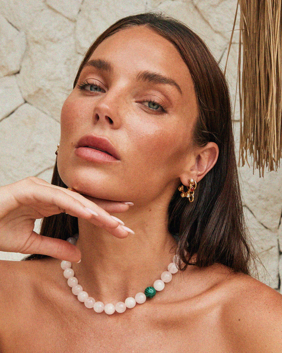 Tilly wearing a pearl necklace against a stone wall background