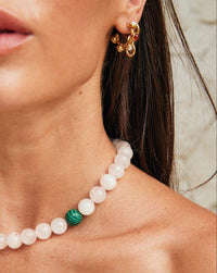 Thumbnail for Close-up of a Tilly Smith wearing a pearl necklace with a green stone and gold earrings.