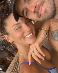 Thumbnail for Man and Tilly Smith posing closely together in a casual setting with wooden beams and hanging plants.