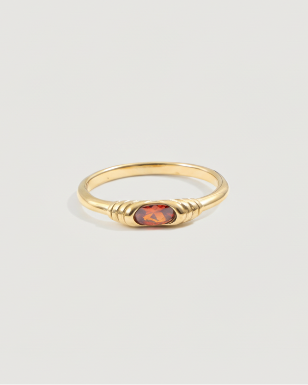 Gold ring with a red gemstone on a light gray background