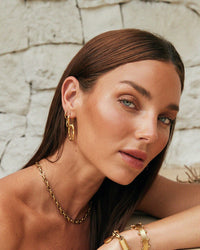 Thumbnail for Tilly Smith wearing gold jewellery against a stone wall background