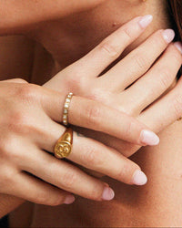 Thumbnail for Close-up of a person wearing gold hoop earrings and rings on a neutral background