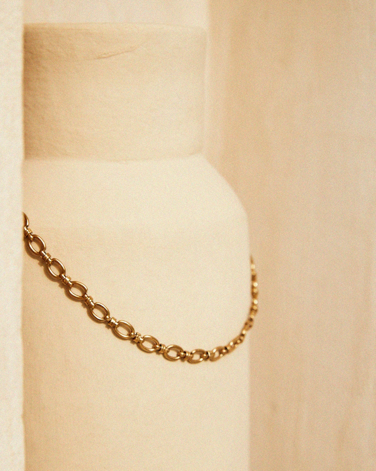 Gold chain necklace on a beige background