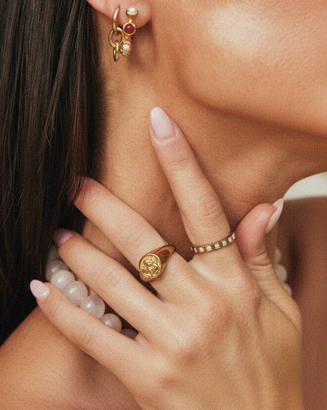 Close-up of Tilly Smith hand wearing gold rings with a blurred background