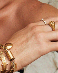 Thumbnail for Close-up of a person wearing gold bracelets, a pearl necklace, and a large wooden bracelet.