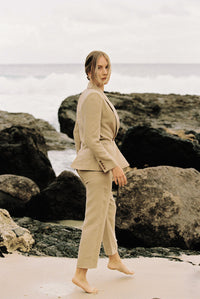 Thumbnail for Model wearing a taupe linen blazer and trouser posing by the beach