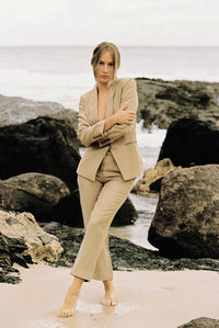 Thumbnail for Model wearing a taupe-coloured suit posing on the beach
