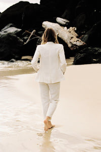 Thumbnail for Back view of model wearing a white linen suit by the beach