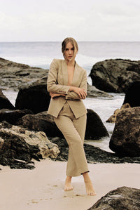 Thumbnail for Model wearing a taupe linen blazer and trouser posing by the beach