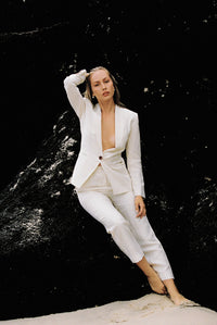 Thumbnail for Model wearing white linen suit posing on a rock by the beach
