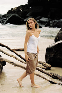 Thumbnail for Model wearing white silk camisole and taupe silk slip skirt posing on the beach