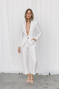 Thumbnail for Model wearing white linen blazer and trousers posing in a studio 