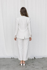 Thumbnail for Back view of a model wearing a white linen suit posing in a studio