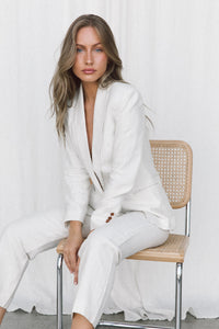 Thumbnail for Model wearing white linen suit posing on a chair in a studio