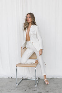 Thumbnail for Model wearing a white linen suit posing on a chair in a studio