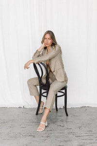 Thumbnail for Model wearing a taupe linen blazer and trouser posing on a chair in a studio