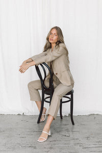Thumbnail for Model wearing a taupe blazer and trouser sitting backwards on a chair in a studio